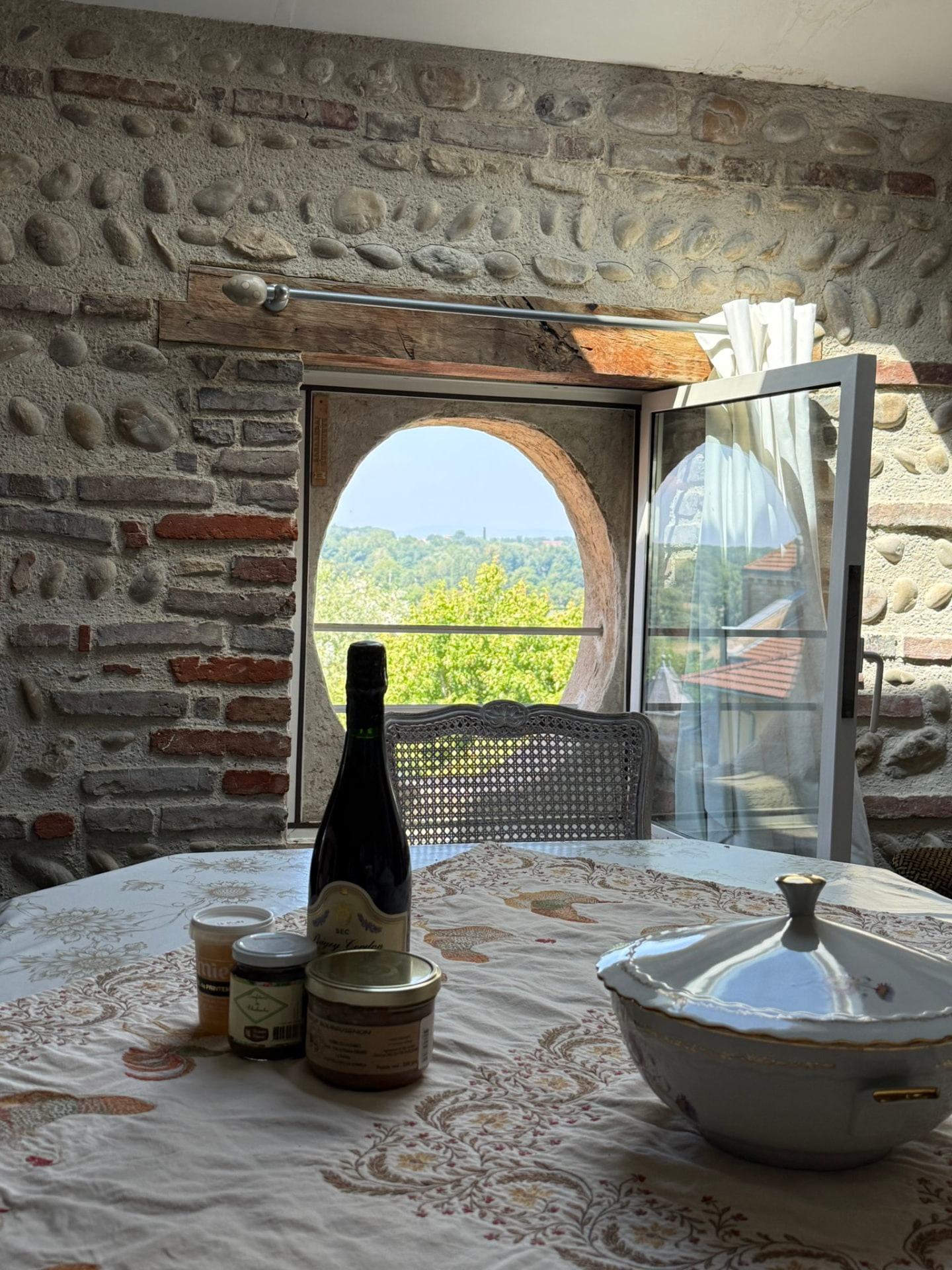Table dressée avec produits du terroir face à l'œil-de-bœuf du salon