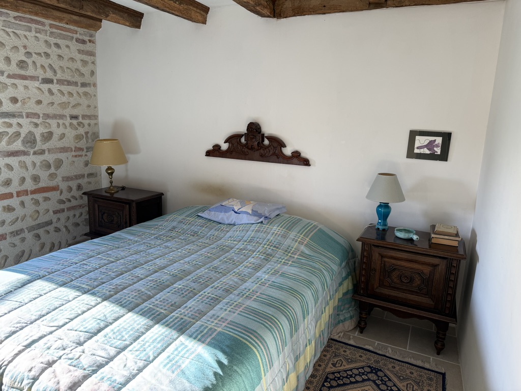 Chambre bleue : lit à couverture écossaise, mur de galets et chevet ancien