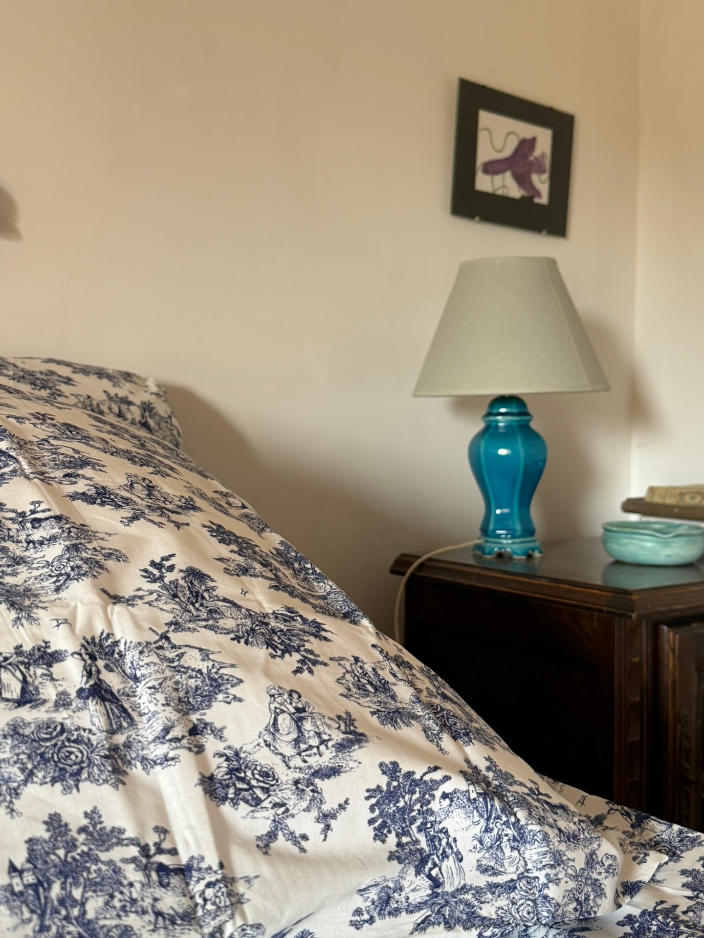 Chambre bleue : lit double, tables de nuit anciennes et mur de galets