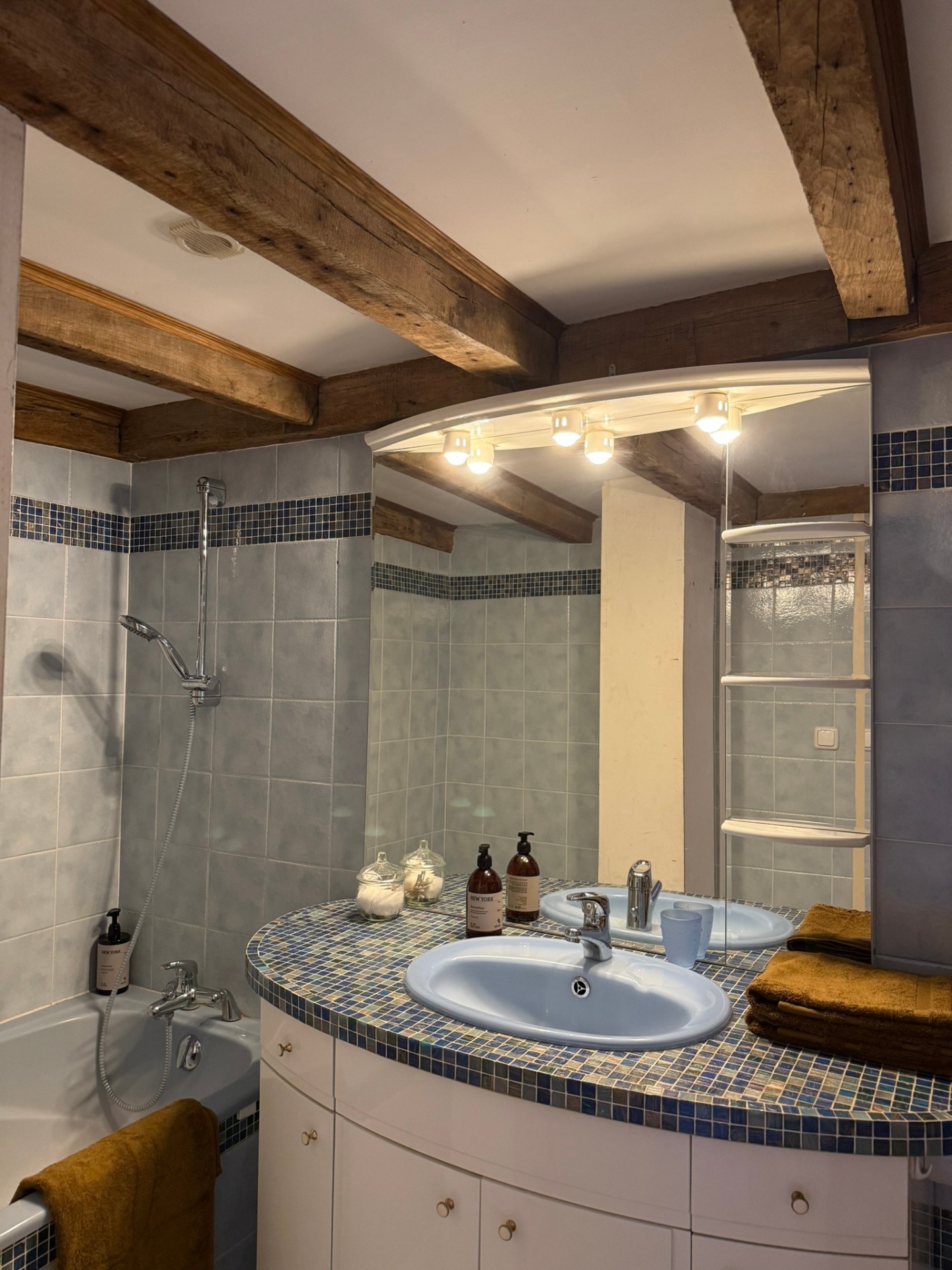 Salle de bain avec baignoire, vasque en mosaïque et poutres anciennes