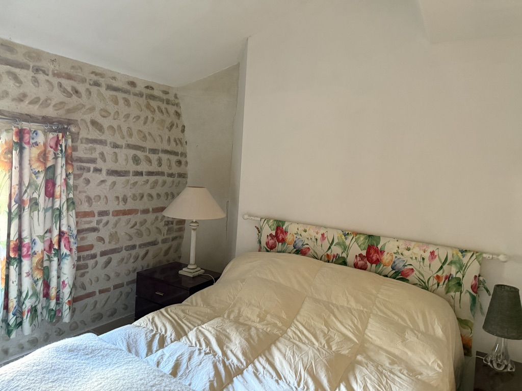 Chambre bleue : tête de lit fleurie et fenêtre habillée de rideaux à fleurs