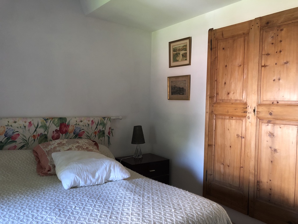 Le lit de la chambre du château avec sa tête de lit fleurie et son armoire ancienne en pin