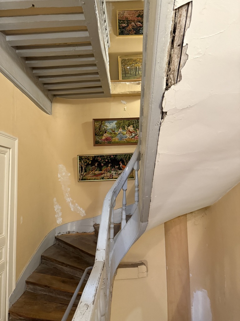 Escalier d'époque à balustres blancs menant à l'appartement des combles