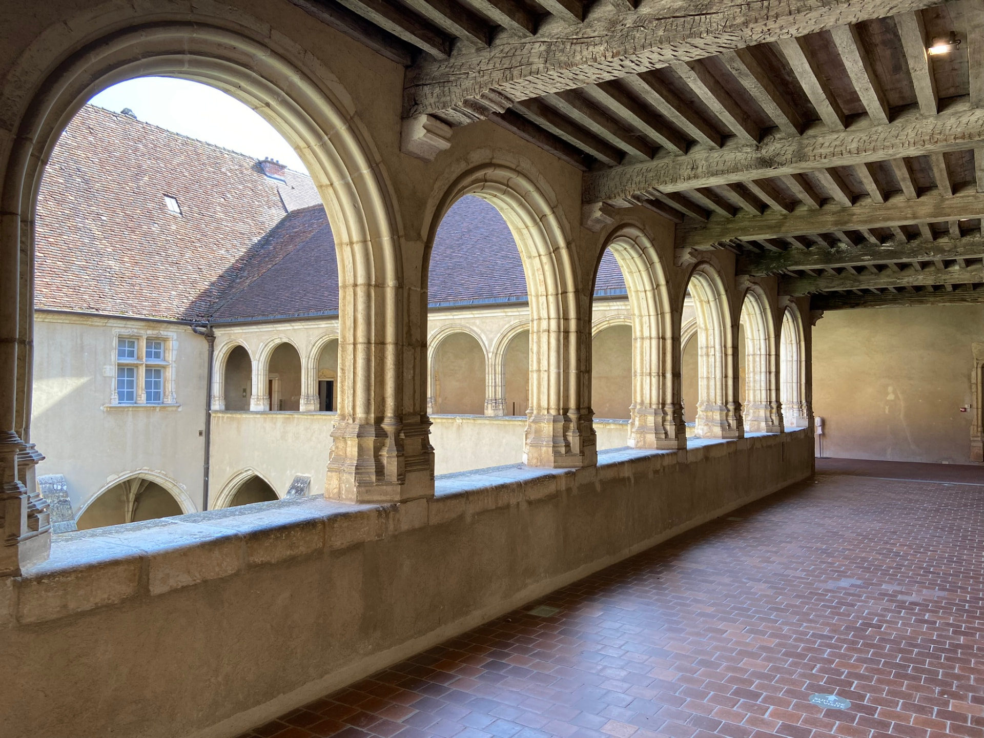 La galerie haute du cloître de Brou, arcades de pierre et plafond à poutres