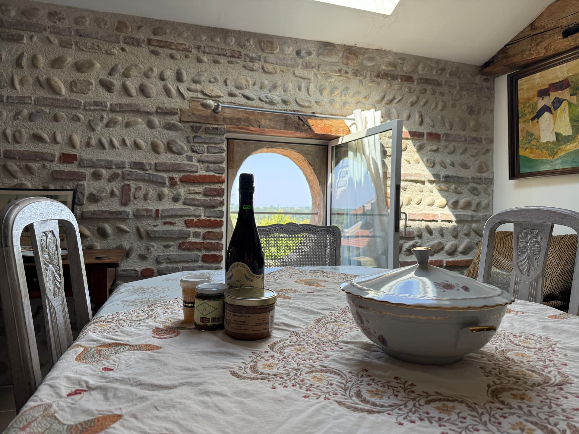 Table dressée avec soupière ancienne devant le mur de galets et briques