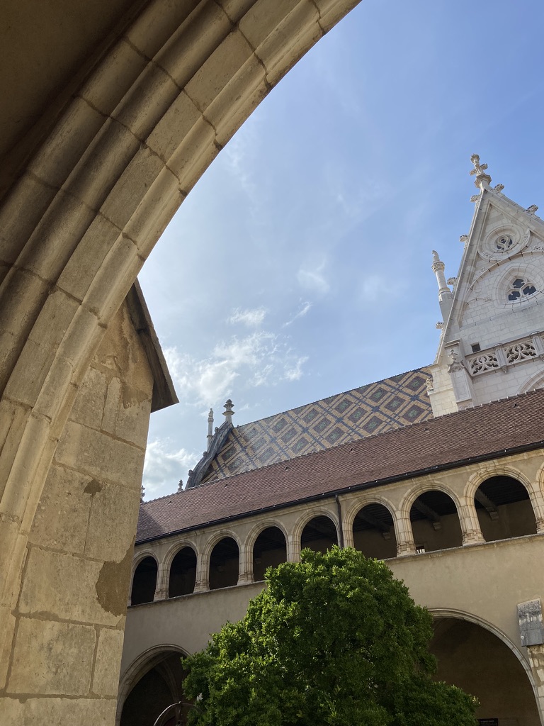 Les tuiles vernissées de Brou aperçues sous une arcade du cloître