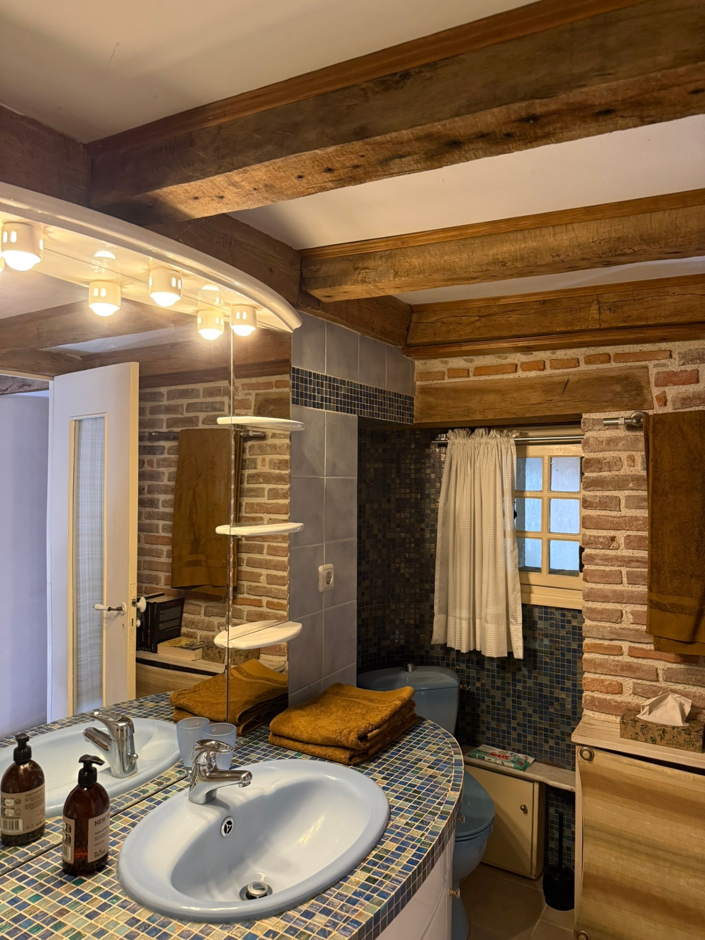 Salle de bain avec baignoire, vasque en mosaïque et poutres anciennes