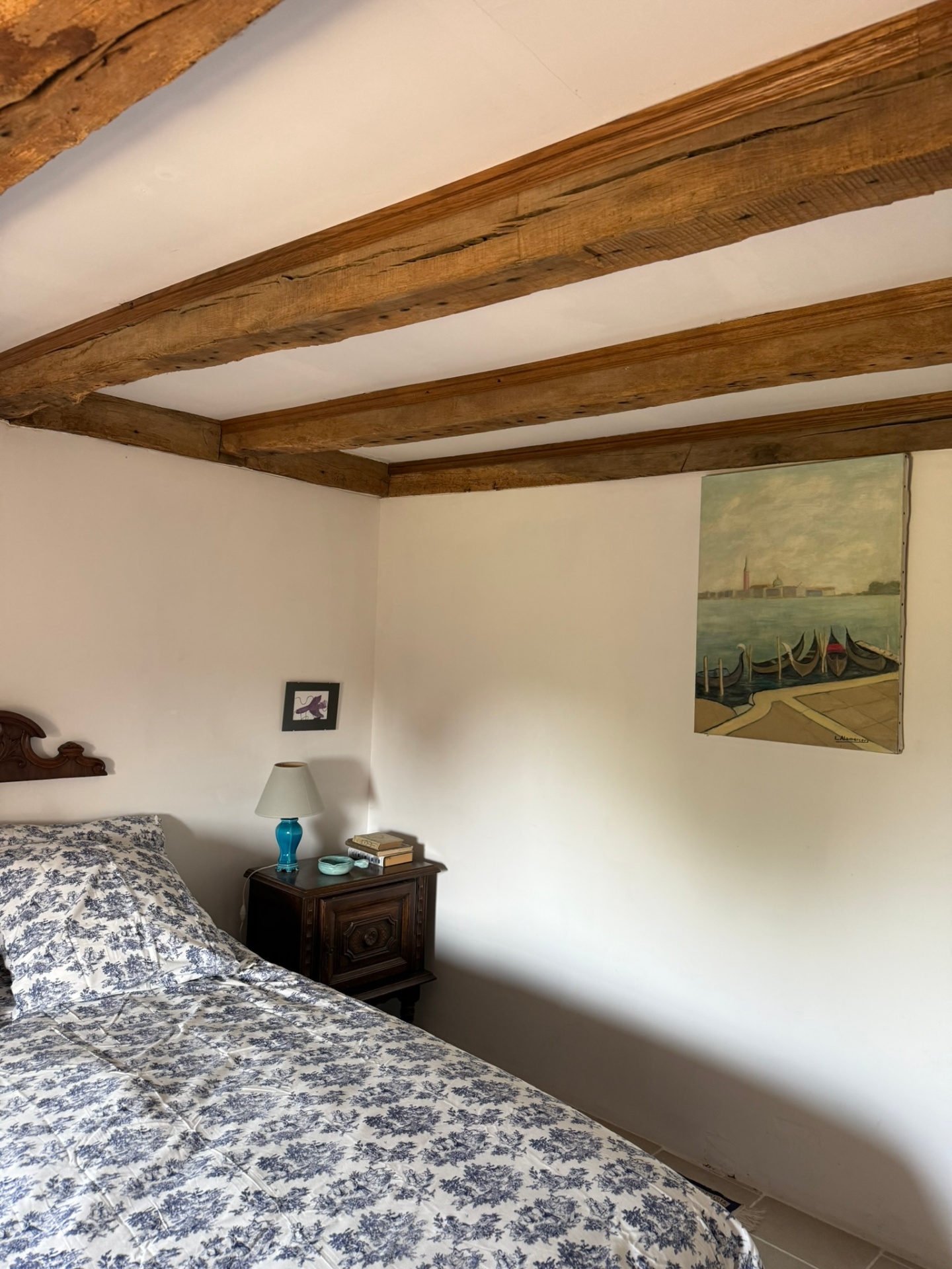Chambre bleue : lit double, tables de nuit anciennes et mur de galets