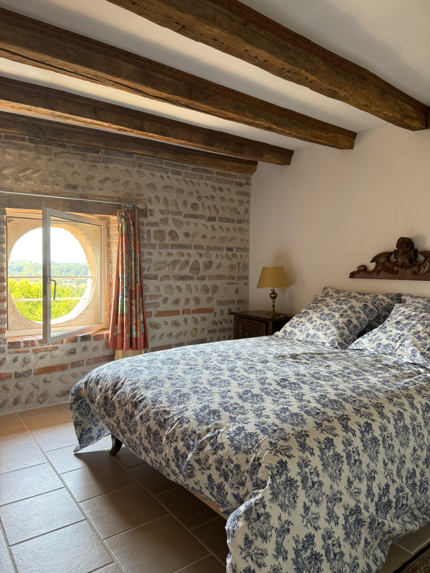Chambre bleue : lit double, tables de nuit anciennes et mur de galets