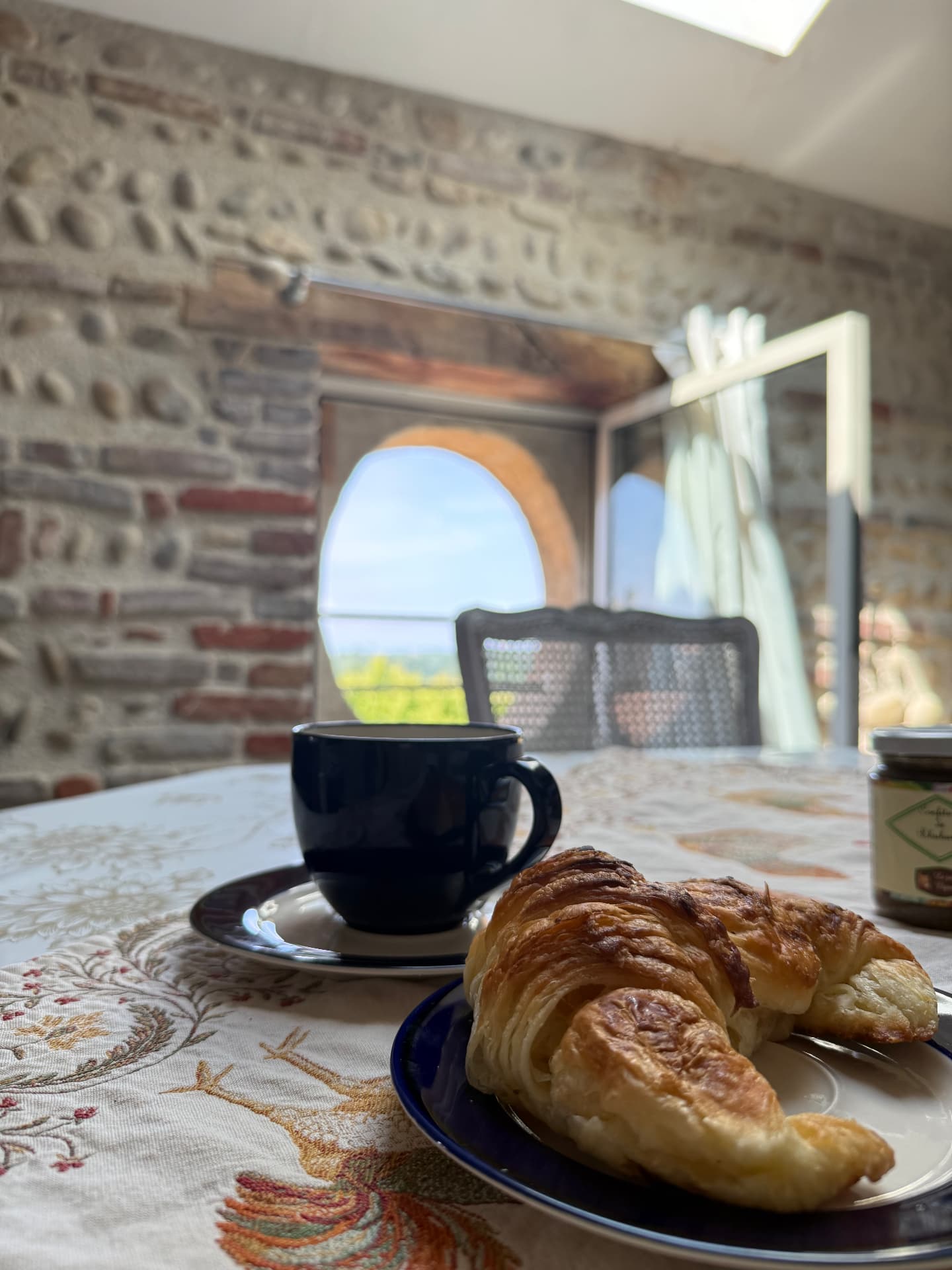 Petit-déjeuner : café et croissant sur la table face à l'œil-de-bœuf