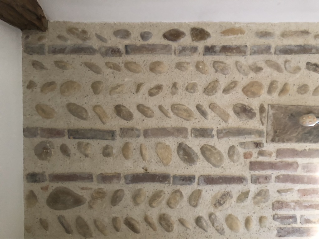 Détail du mur de galets et de briques en épi, typique de la Dombes