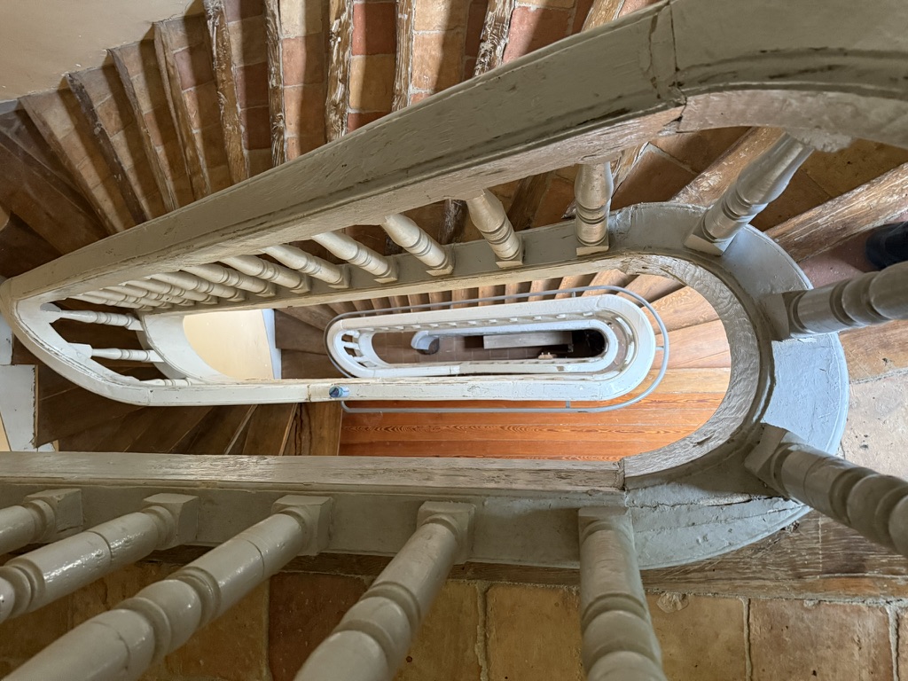 Cage d'escalier en colimaçon avec balustres blancs et marches en bois — vue plongeante