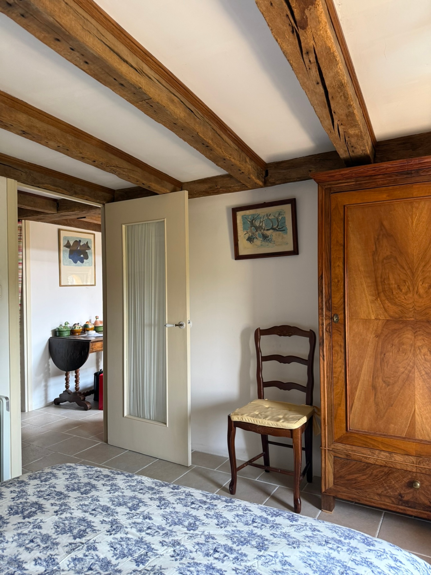 Chambre bleue : lit double, tables de nuit anciennes et mur de galets