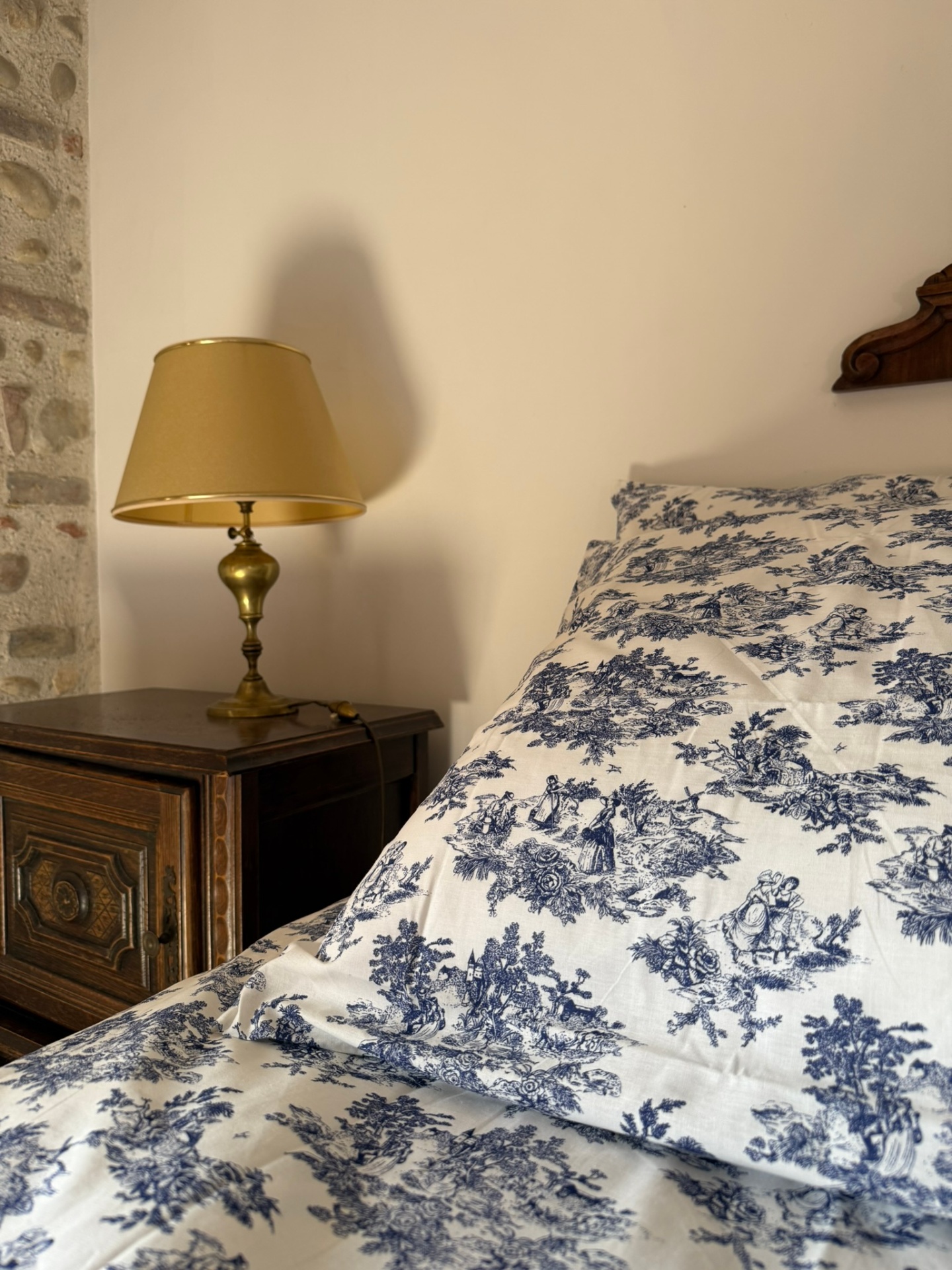 Chambre bleue : lit double, tables de nuit anciennes et mur de galets