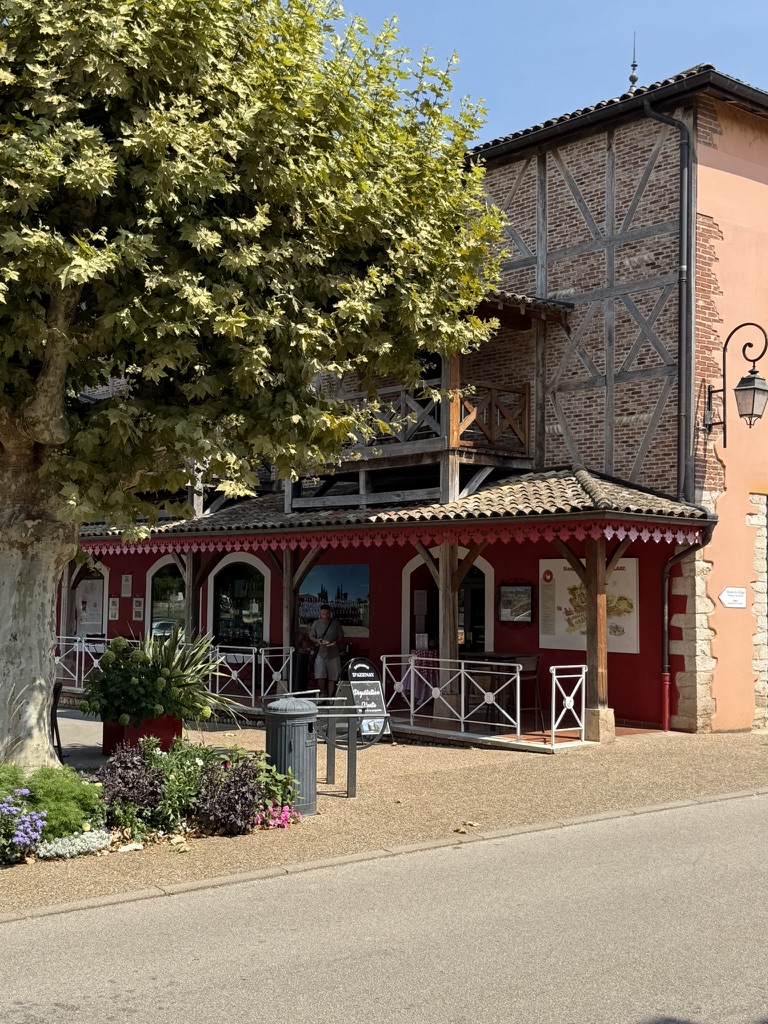 La boutique aux pans de bois et auvent rouge sous le platane de Vonnas